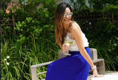 Moda 5 mujer con lentes y falda sentada en una terraza