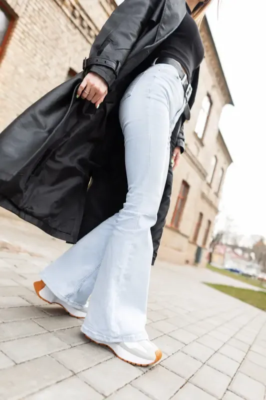 fashionable girl stylish casual clothes with black coat vintage highwaisted flare jeans with sneakers city